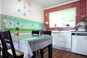 A kitchen with a brick wall, a window with a plant, and a table with chairs.