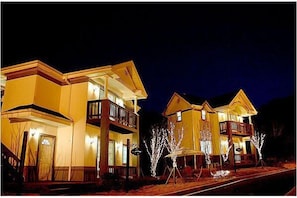 A two-story building with a balcony on the second floor, a front door, and a staircase leading to the entrance.