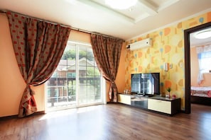 A room with a large sliding glass door, a flat-screen TV, and a patterned wall.