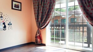 A room with a large window, a patterned curtain, a framed picture on the wall, and a wall decal of cats. - Yongin Doongji Art Village Pension (Yongin)