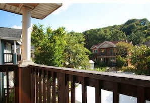 A wooden deck with a view of a house surrounded by trees.