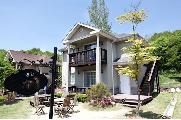 A two-story house with a balcony, a staircase, and a small deck area.