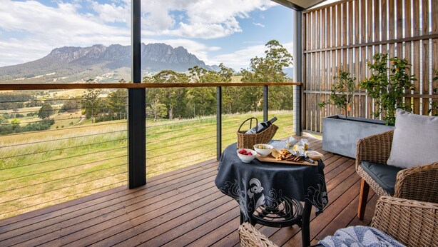 A balcony with a table set for a meal, overlooking a mountainous landscape.