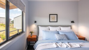 A bedroom with a bed, a nightstand, a window, and a framed picture on the wall.