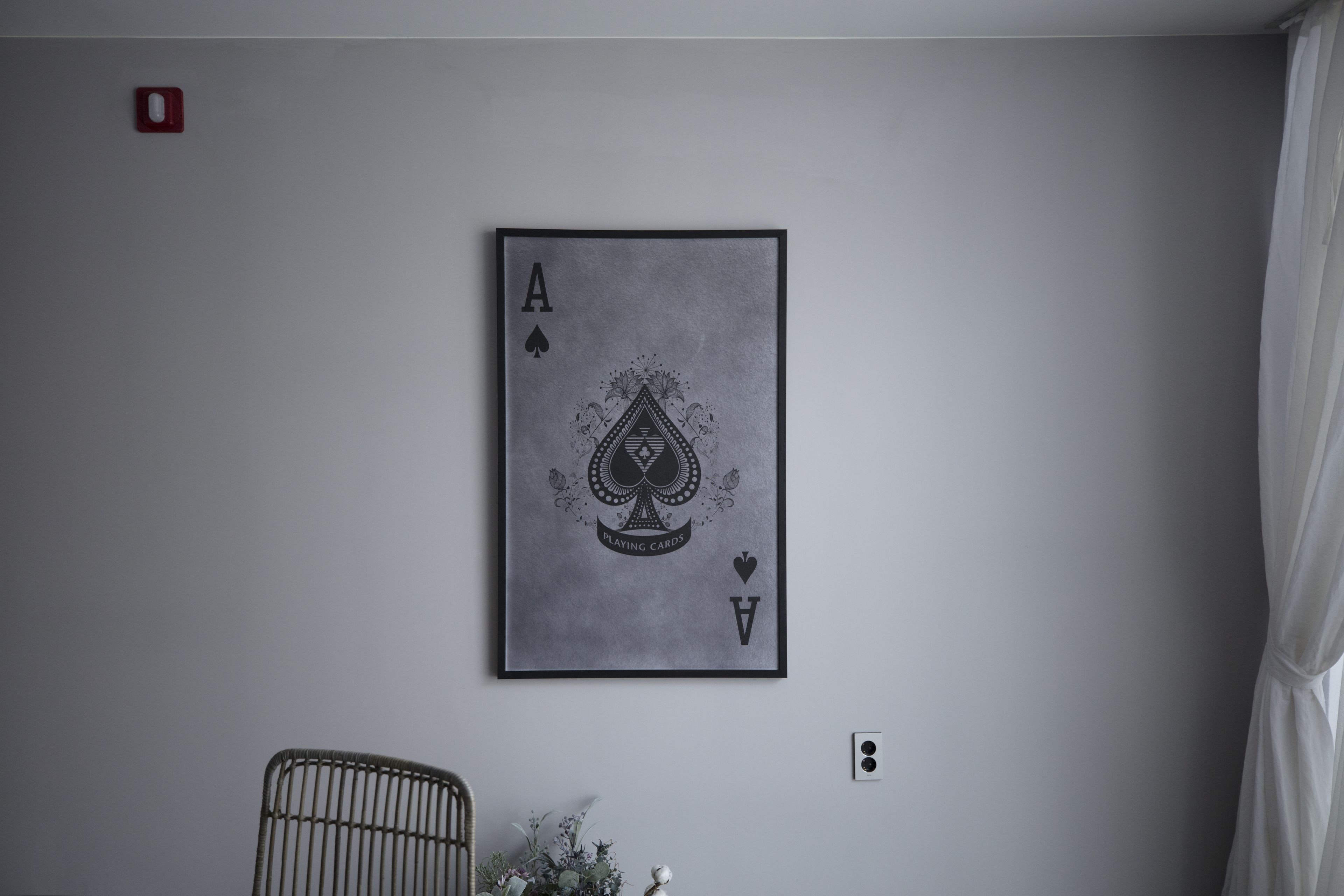 A framed playing card, Ace of Spades, on a plain wall.