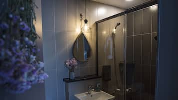 A modern bathroom with a glass shower enclosure, a white sink, and a toilet.