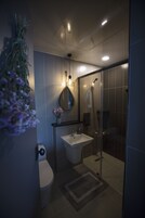 A modern bathroom with a glass shower enclosure, a white sink, and a toilet.