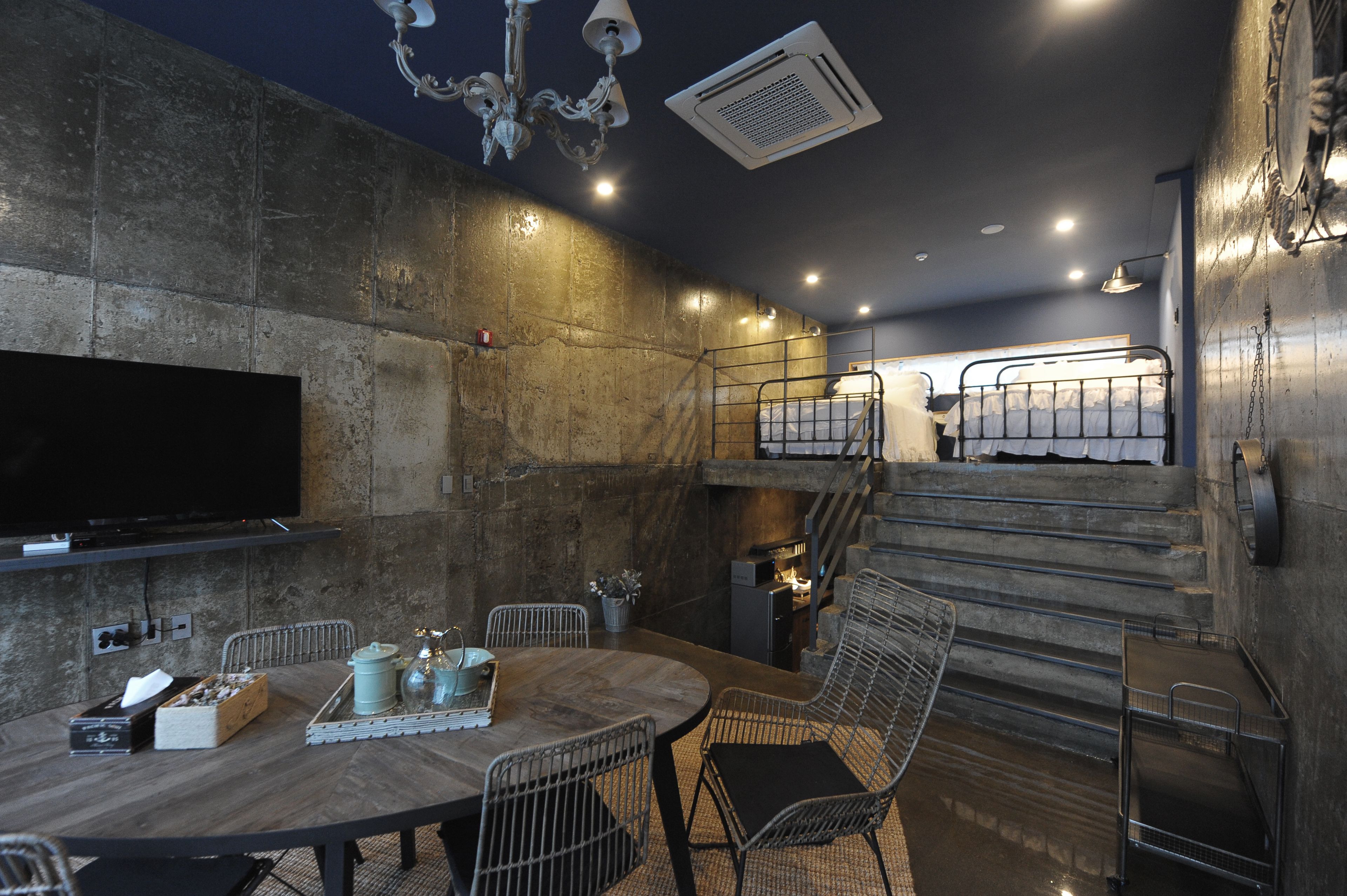 Un intérieur moderne comprenant un coin repas, un téléviseur fixé au mur et un escalier menant à un niveau supérieur.