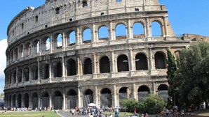 A large, historic coliseum with multiple arches and columns, surrounded by a grassy area and trees. - Take Me Rome - Modern Apartment near Colosseum (Roma)