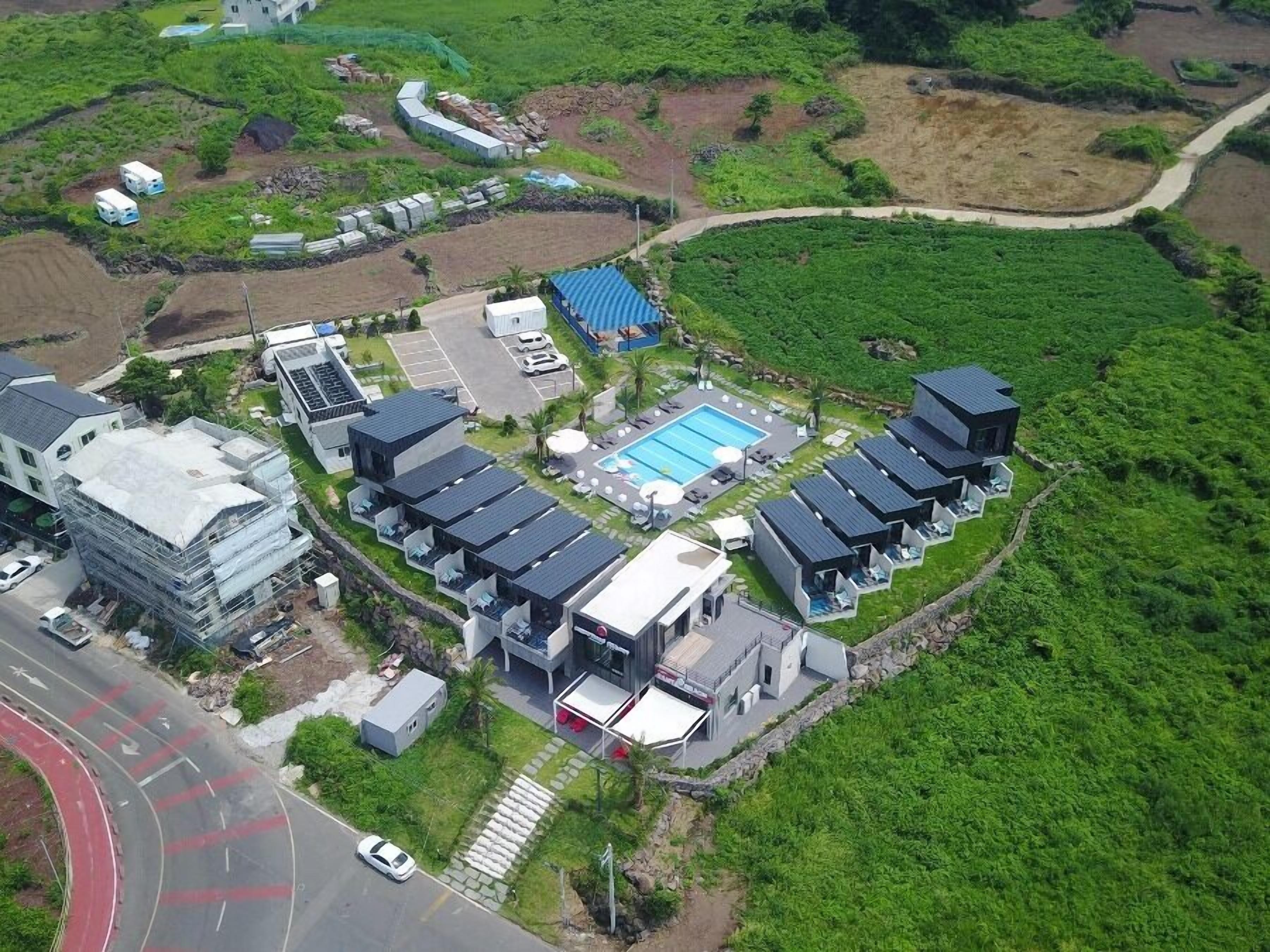 A modern hotel with multiple guest rooms, a swimming pool, and a landscaped garden.