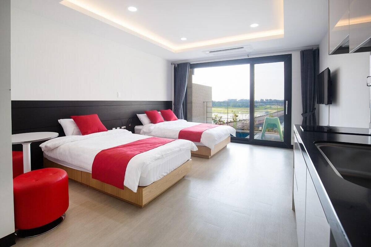 Una habitación de hotel moderna con dos camas, una mesa de comedor y una cocina.