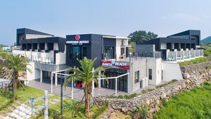 A modern building with a 'Café Santa Beach' sign, featuring a flat roof and a stone wall surrounding the property. - Christmas Resort (Jeju City)