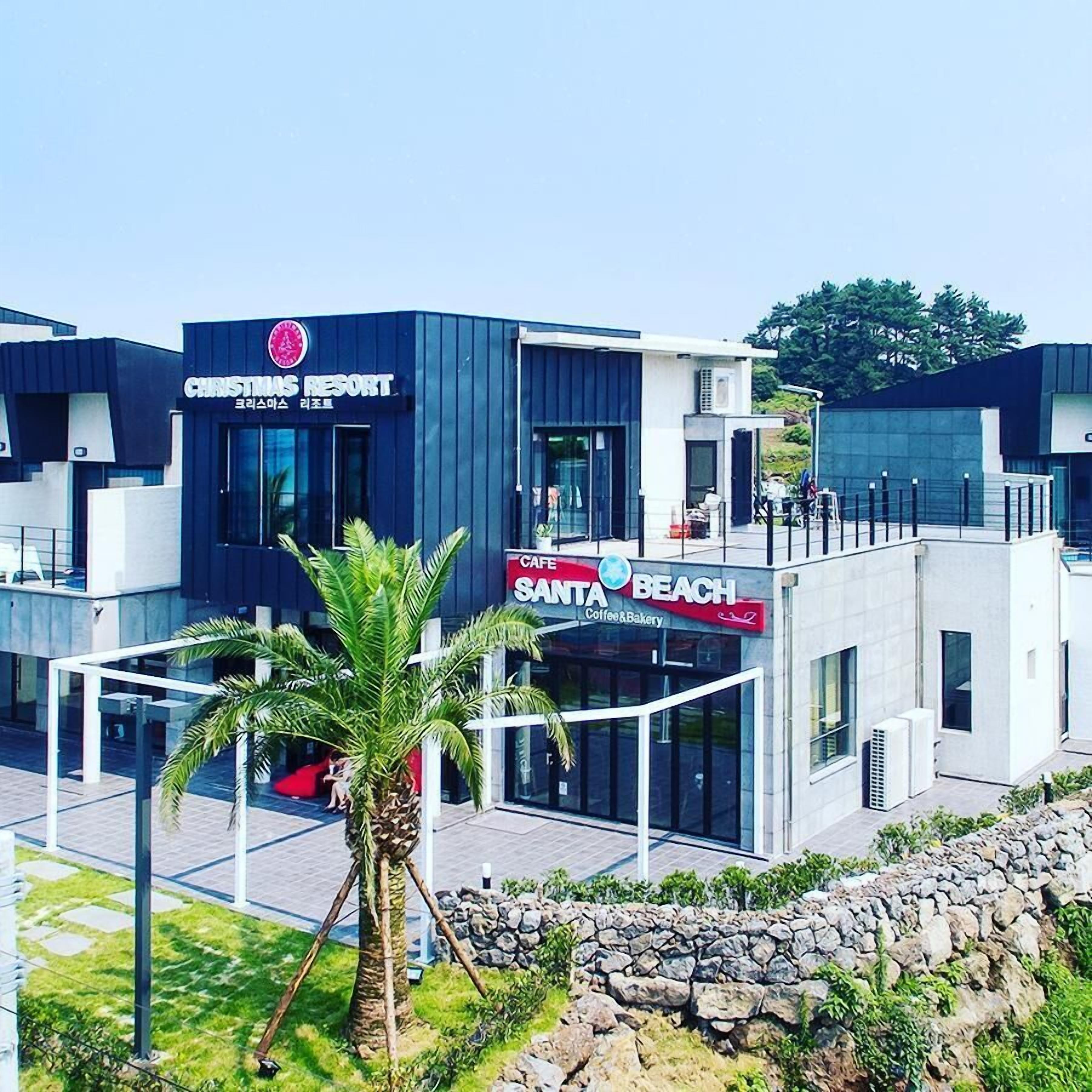Un edificio moderno con un letrero que dice 'Christmas Resort' y 'Santa Beach Coffee & Bakery'.