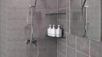 A modern shower area with a handheld showerhead, a wall-mounted faucet, and a shelf with toiletries.