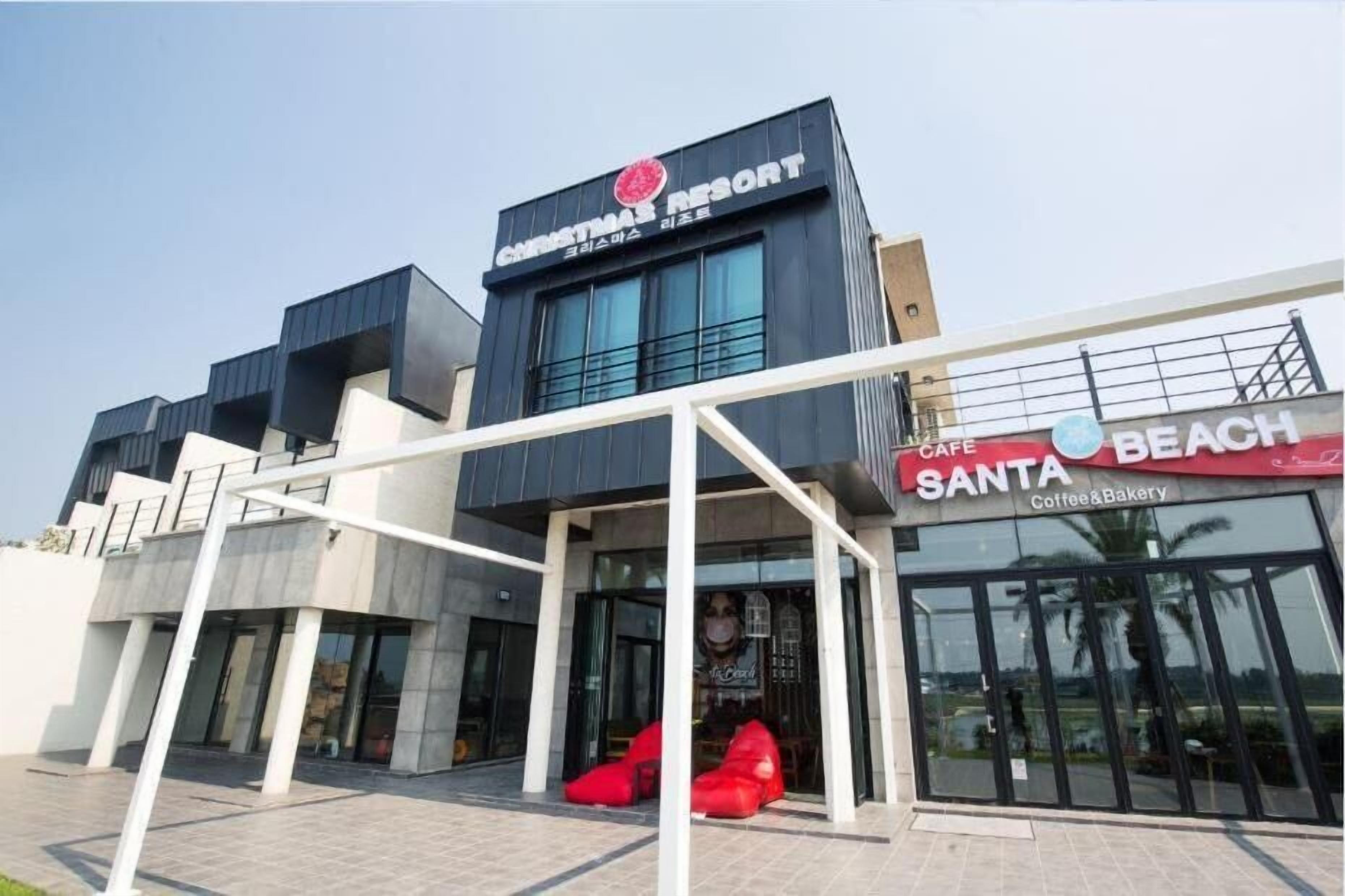 Um edifício moderno com uma placa para 'Christmas Resort' e uma cafeteria 'Santa Beach'.