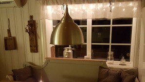 Un'accogliente sala da pranzo con un tavolo in legno, una candela e un'ampia lampada a sospensione.