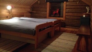 Una camera da letto mansardata accogliente, con un letto di legno, una finestra e un cavallino giocattolo rosso, oltre a un tavolino.