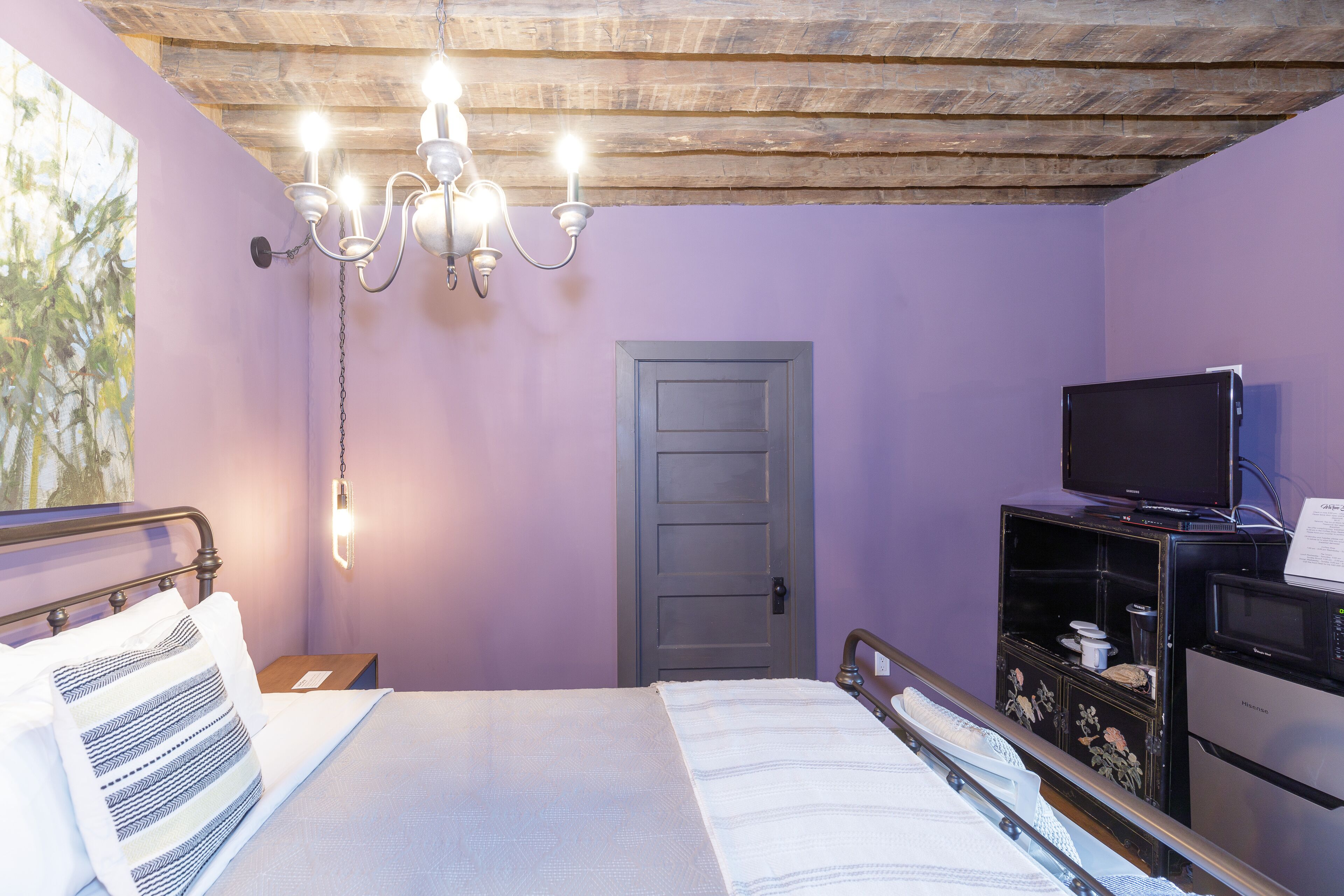 Une chambre à coucher avec un lit, une télévision, un plafond en bois et une porte.