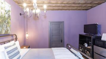Une chambre à coucher avec un lit, une télévision, un plafond en bois et une porte.