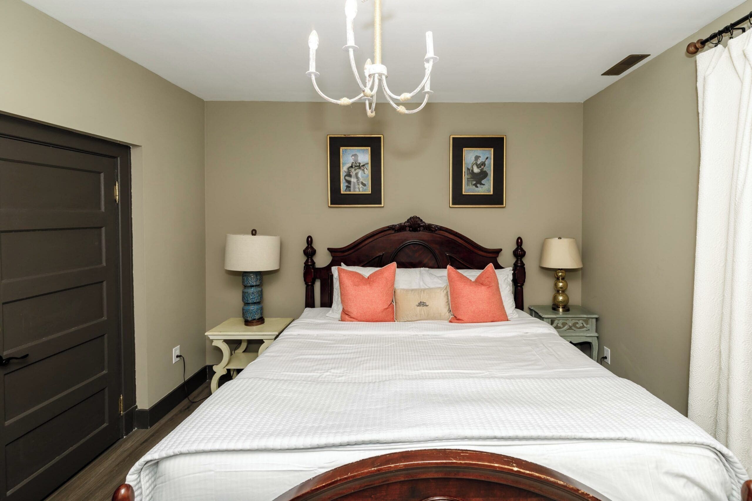 A neatly made bed with a wooden headboard, two bedside lamps, and two framed pictures on the wall.