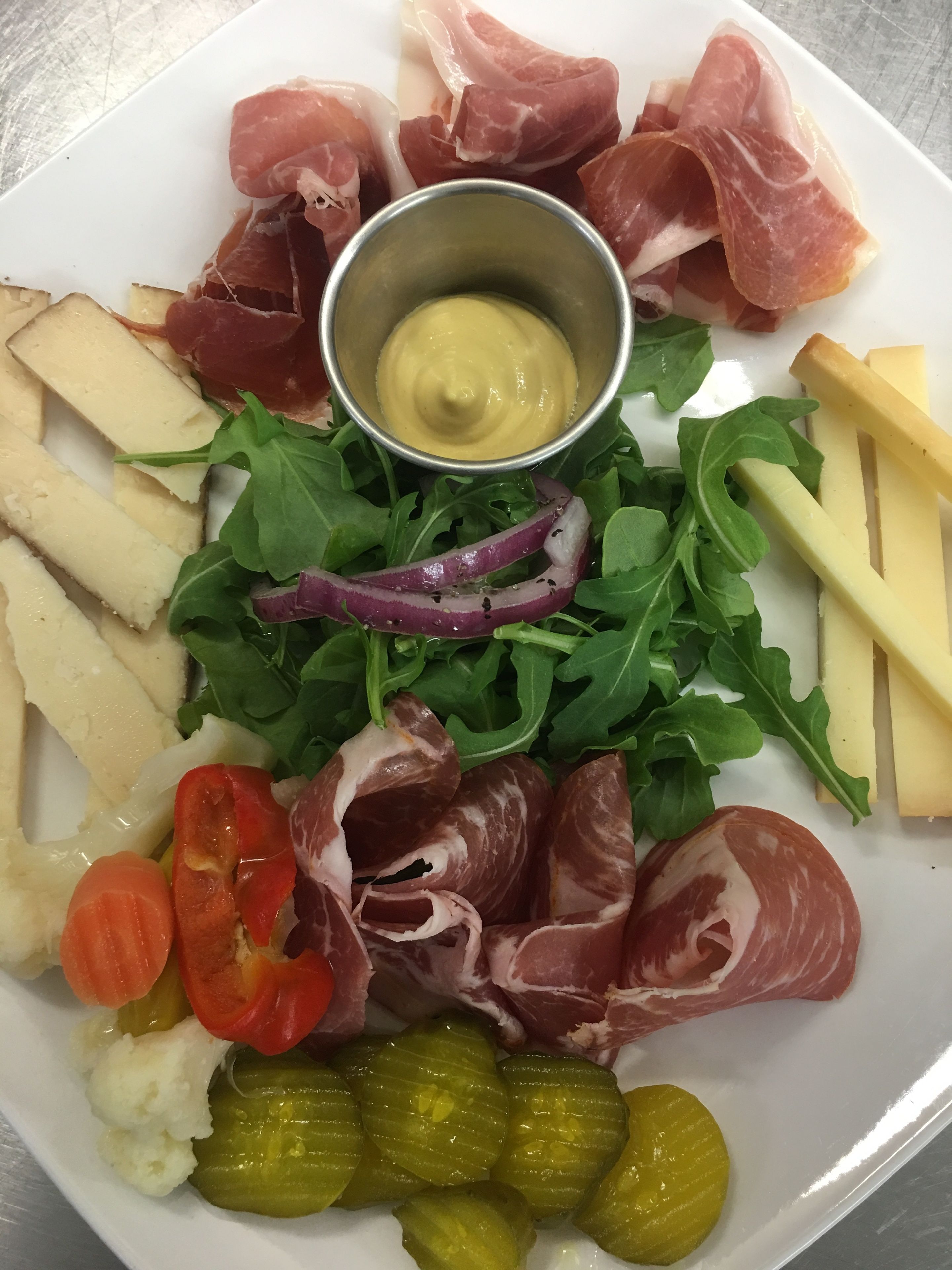 En skifer med forskellige slags pålæg, oste, syltede grøntsager og salat.
