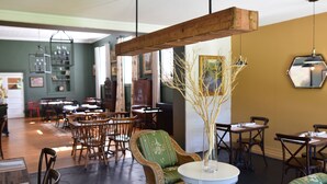 A dining area with wicker furniture, a white table, and a wooden beam ceiling. - The Inn At Warm Springs (Warm Springs)
