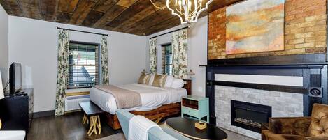 Une chambre confortable avec un grand lit, une cheminée et un plafond rustique.