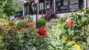 A building with a porch and a garden with various plants and flowers. - The Inn At Warm Springs (Warm Springs)