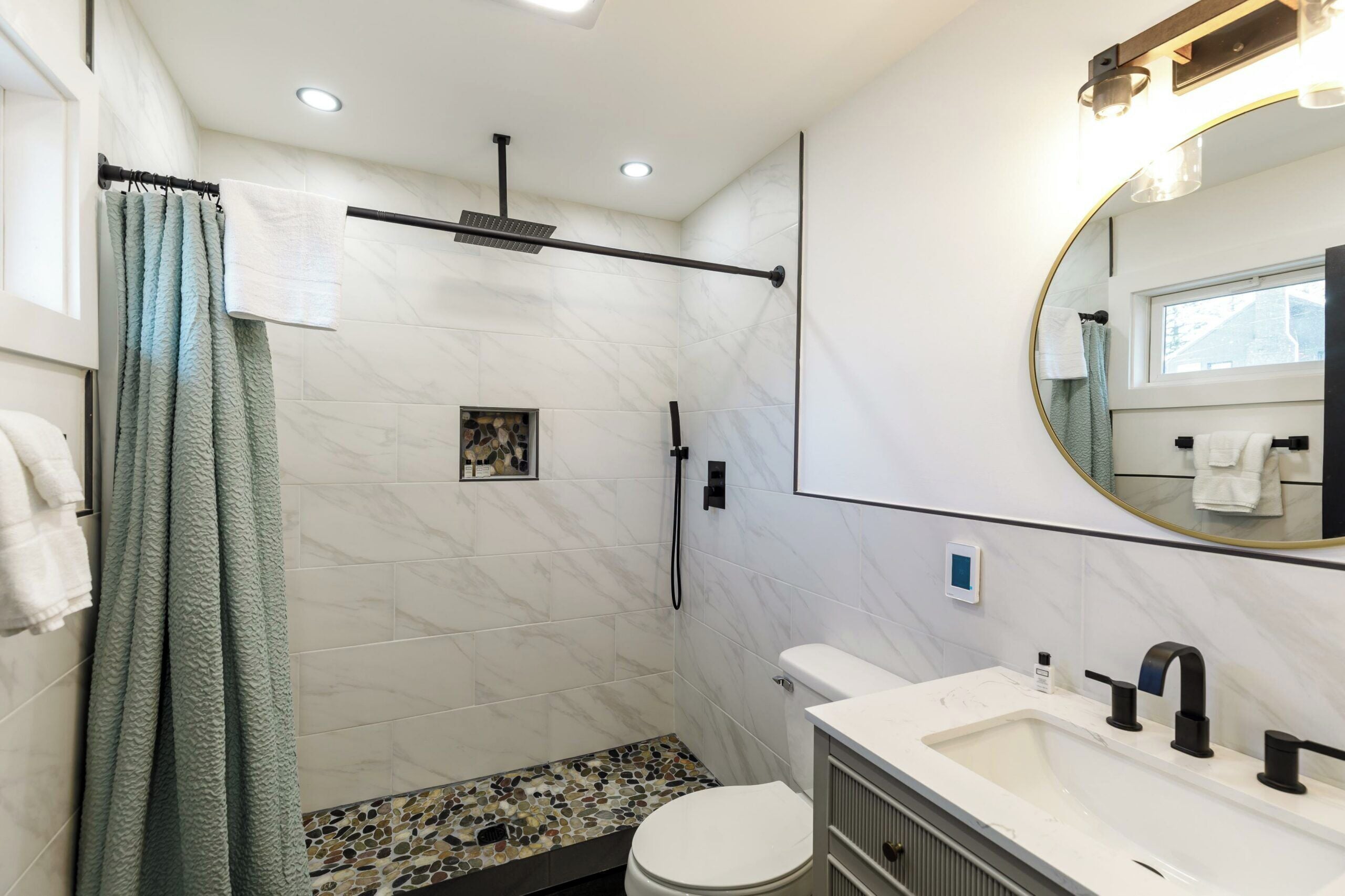A modern bathroom with a shower, toilet, and sink.