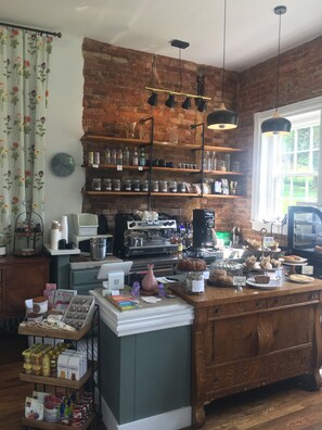 A rustic kitchen with brick walls, wooden shelves, and a variety of food items displayed.