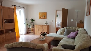 A living room with a sofa, a coffee table, a cabinet, and a potted plant. - Apartment in a quiet central location in the country (Thale)