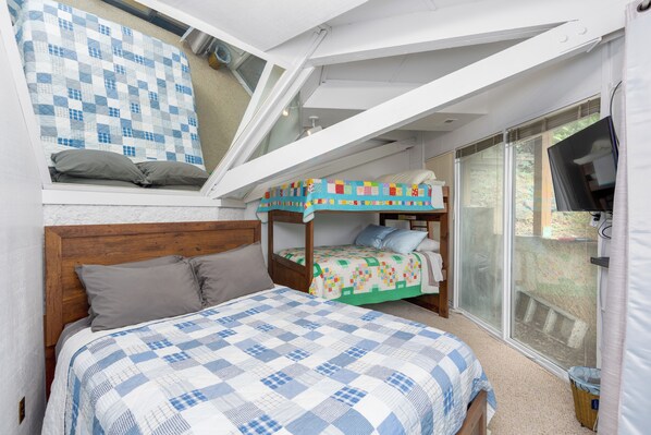 Un dormitorio con una cama grande, una litera y un tragaluz.