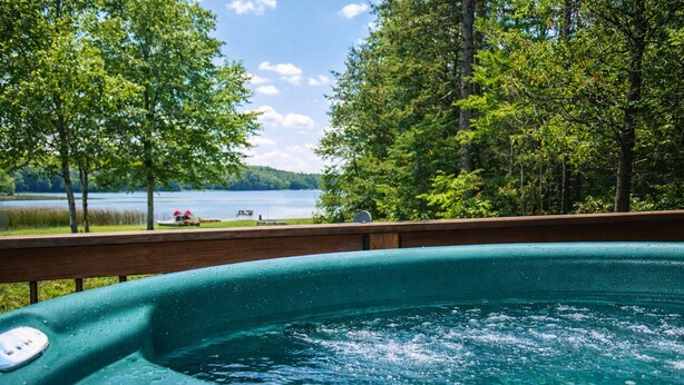 A hot tub with a view of a lake and forest. - The River's Edge Hot Tub Wi-Fi Riverfront Pet Nature Relax Ski Stargaze Relax!  (Indian River)