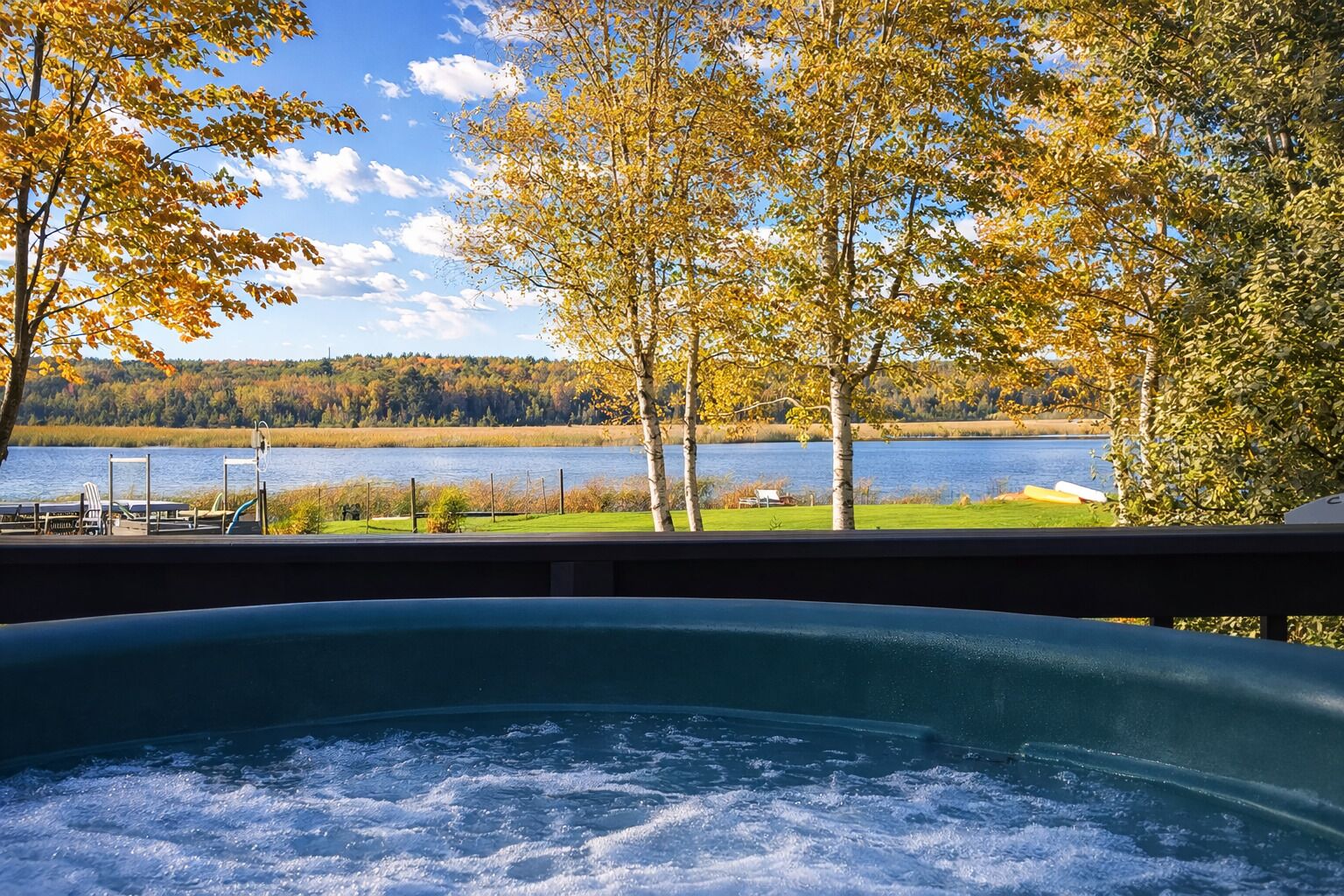 Un jacuzzi con vistas a un lago, árboles y un muelle.
