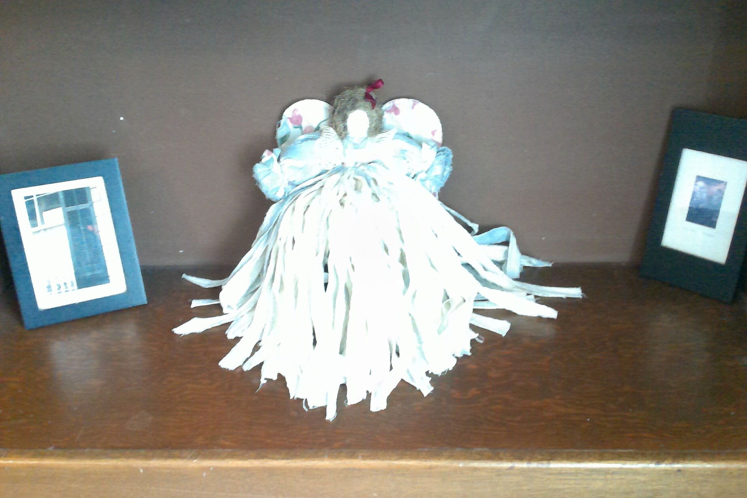 A doll with a blue and white dress on a wooden surface.