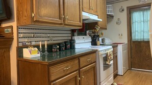 A kitchen with wooden cabinets, a white stove, and a tiled backsplash. - Beaver Lake Rent Cabin  Lg Covered Deck Room~Firepit~Quiet~Private~7Mi Rogers AR (Rogers)