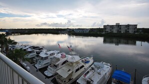 A marina with several boats docked, a building in the background, and a calm body of water.