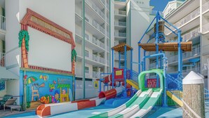 A children's play area with slides and climbing structures, surrounded by multi-story buildings with balconies.