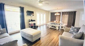 A living room with a sofa set, a dining table, and a TV mounted on the wall. - What a view of Lake Cherokee  (Bean Staion)