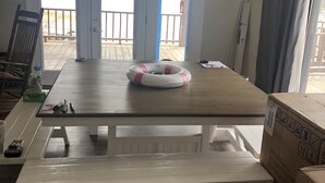 Een eetgedeelte met een houten tafel, een bank en uitzicht op een meer door glazen deuren.