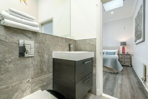 A modern bathroom with a marble wall, a sink, and a mirror.