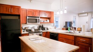 Une cuisine moderne avec des meubles en bois, un réfrigérateur noir, un four à micro-ondes, une cuisinière et un évier.