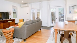 Un salon moderne avec un canapé gris, une table basse en bois et une table à manger avec des chaises.