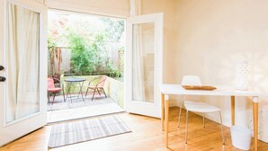 Une pièce dotée d’une porte-fenêtre coulissante donnant sur une terrasse aménagée avec du mobilier d’extérieur.