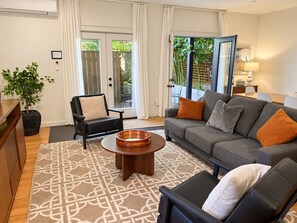 A modern living room with a sofa, armchairs, a coffee table, and a potted plant.