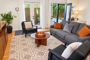 Una sala de estar moderna con un sofá gris, un sillón negro y una mesa de centro redonda de madera.