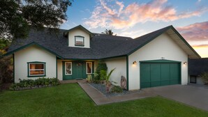 Una casa de dos pisos con puerta verde, garaje y césped bien cuidado.
