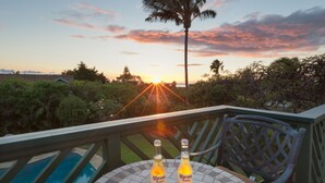 Dos botellas de Corona Extra sobre una mesa con vista al atardecer y palmeras.