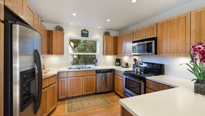 Una cocina moderna con armarios de madera, electrodomésticos de acero inoxidable y un amplio ventanal que proporciona luz natural.