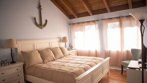 Un dormitorio con una cama grande, dos mesitas de noche con lámparas, una silla y un ventilador de techo.